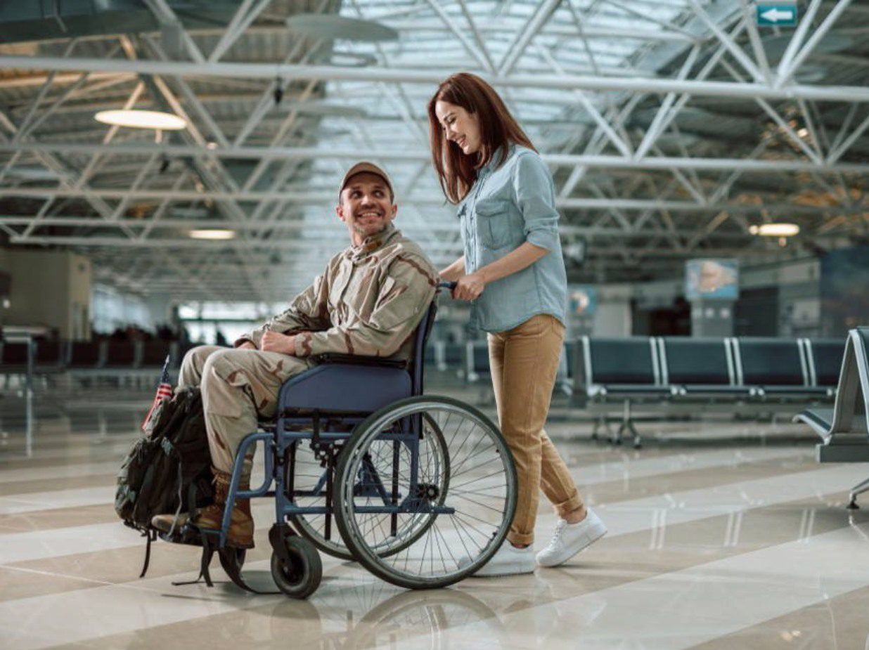 Woman pushing a man in a wheelchair at an airport.
